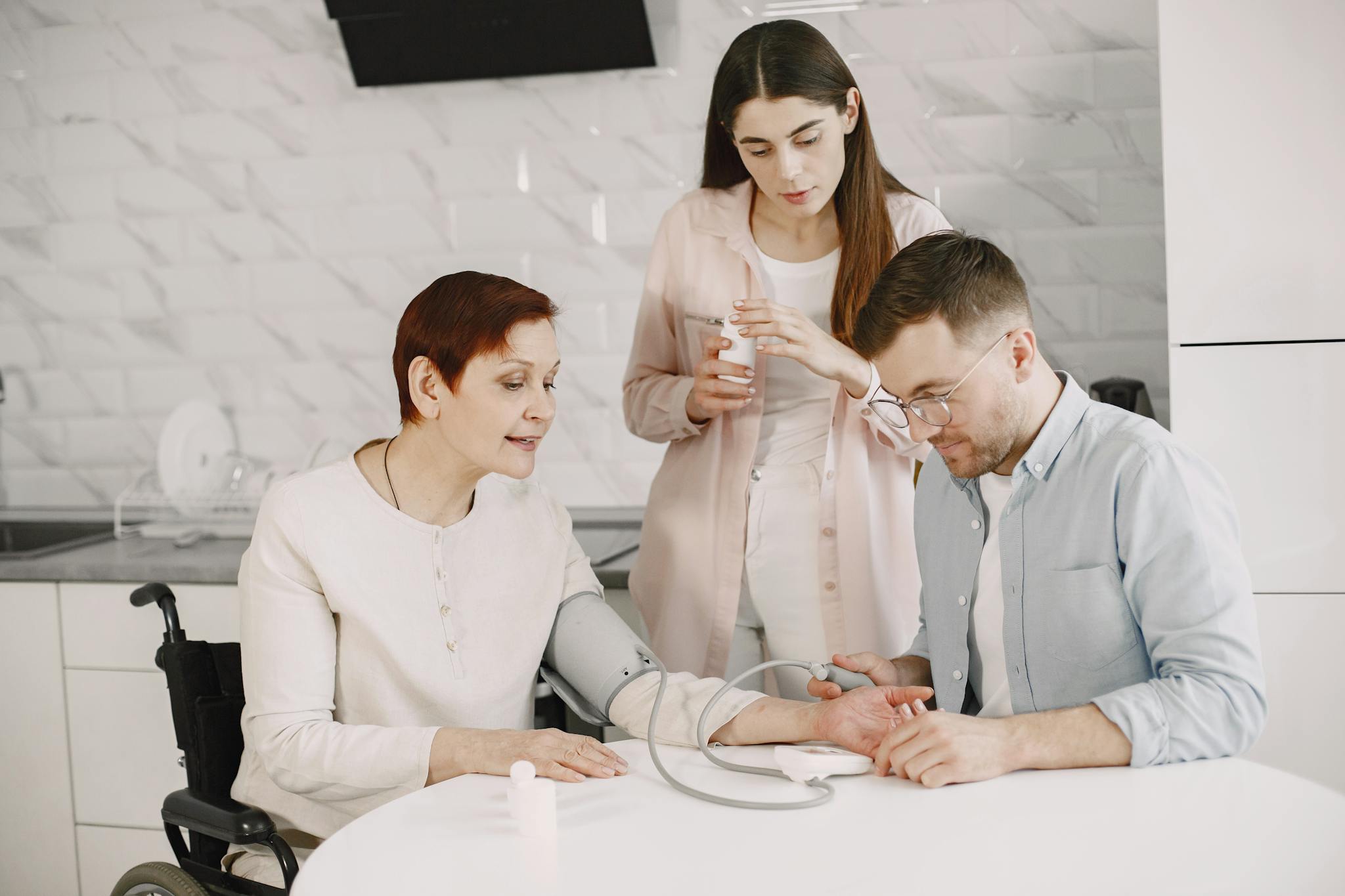 A family member assists a senior in a wheelchair with a blood pressure check, symbolizing care and wellbeing.