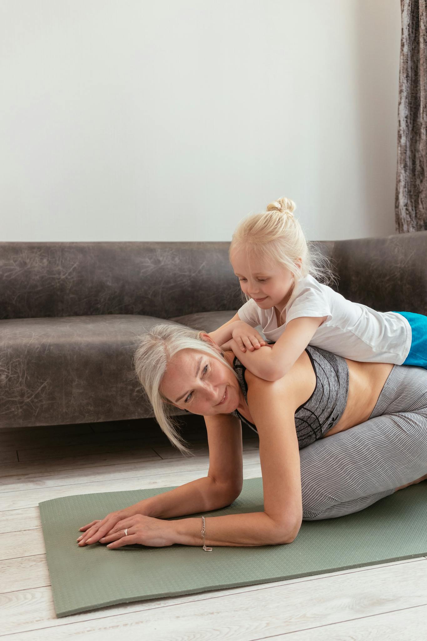 Senior woman and young girl enjoying yoga on mat at home, bonding through exercise.